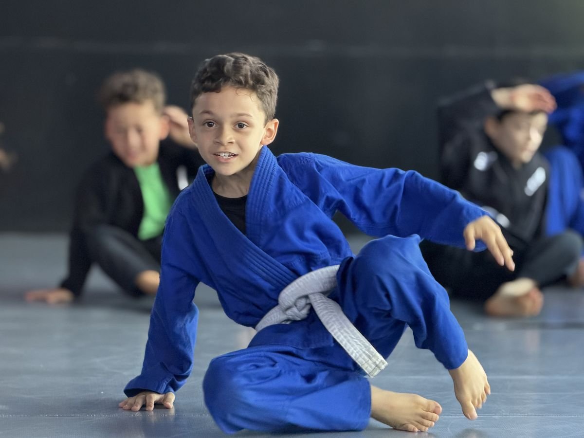 Menino de quimono azul sorrindo no treino