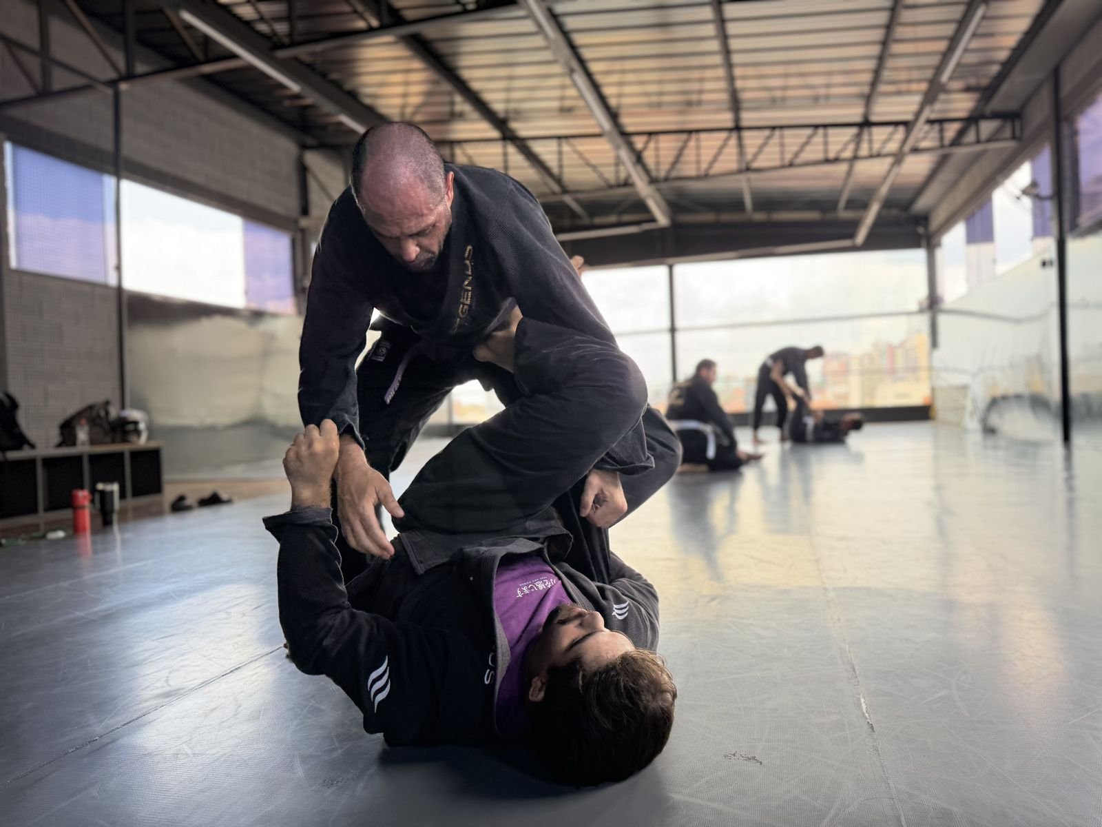 Professor passando a guarda de um aluno faixa roxa no tatame do CT Stronda